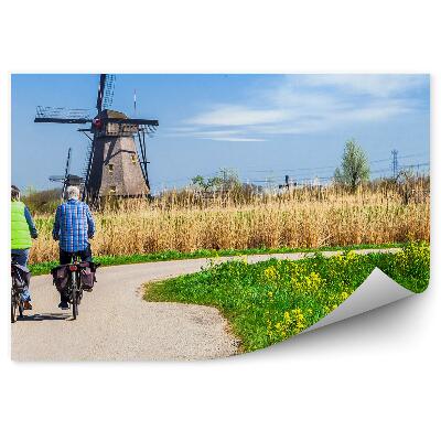 Fototapeta na stenu Moški kolesarji na poti s pogledom na mlin na veter