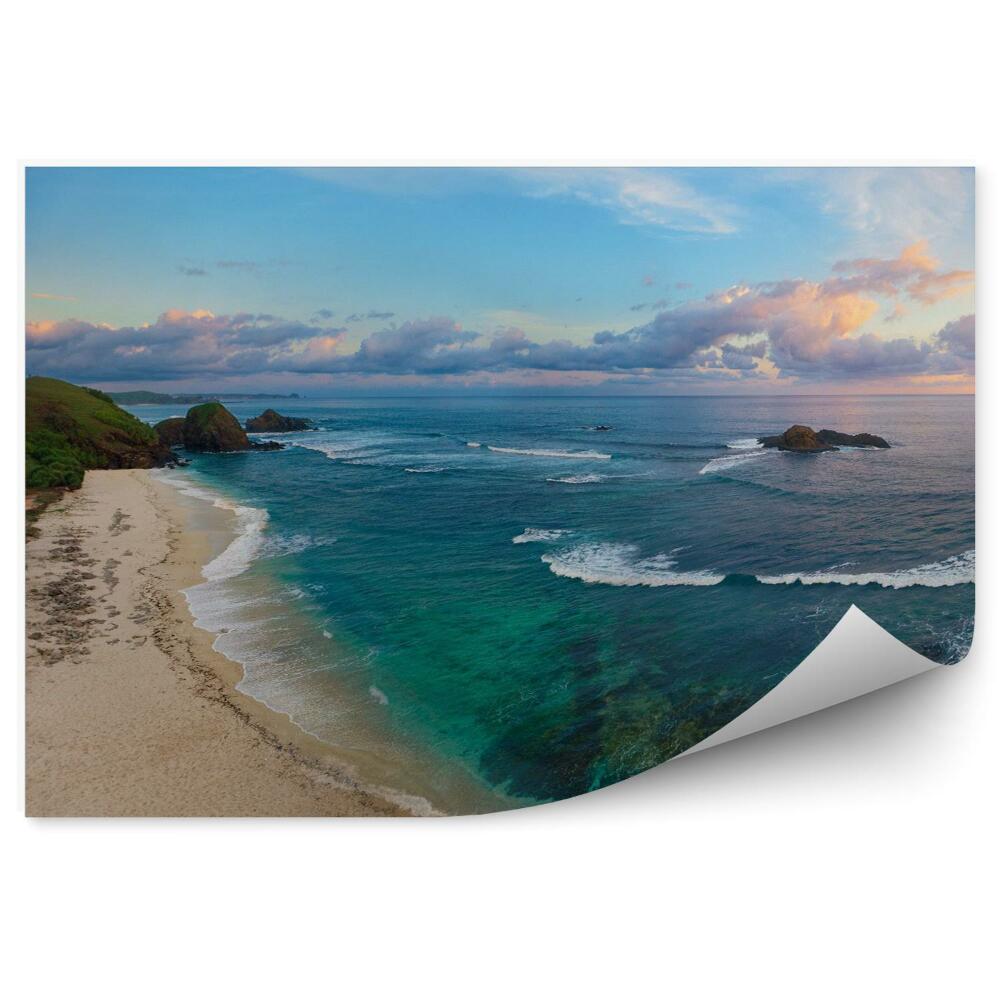 Fototapeta Panoramatický pohľad na tropickú pláž so surfistami pri západe slnka.
